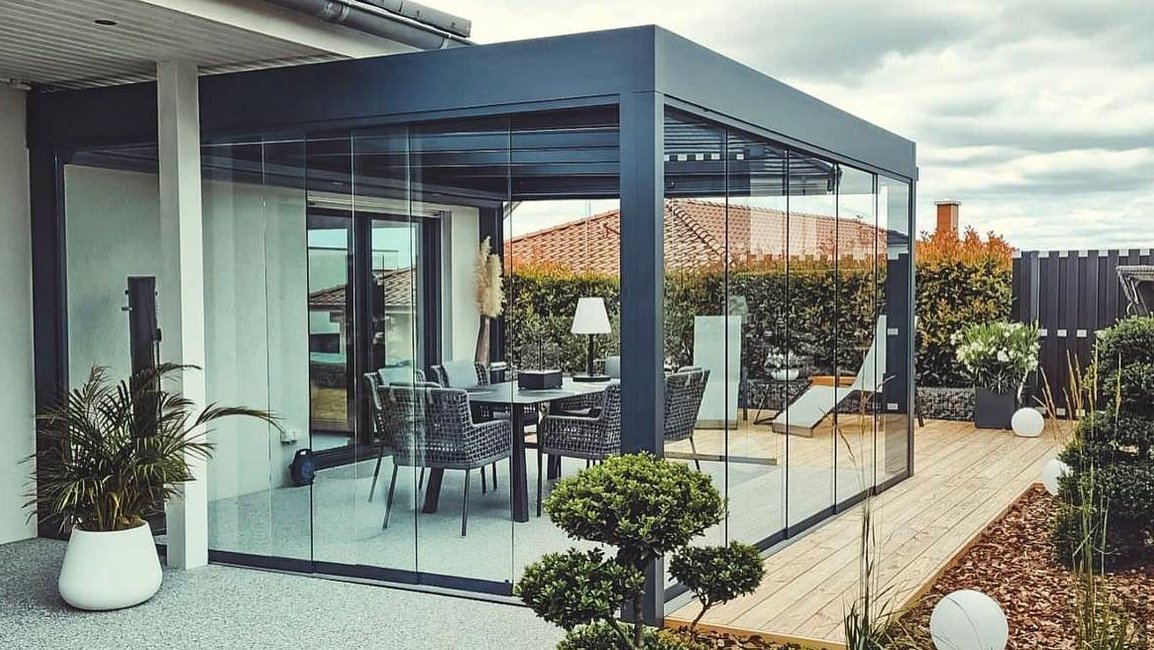 Moderní hliníková pergola s bezrámovým zasklením a jídelním posezením na terase – celoroční využití díky zasklení Hezký stín.