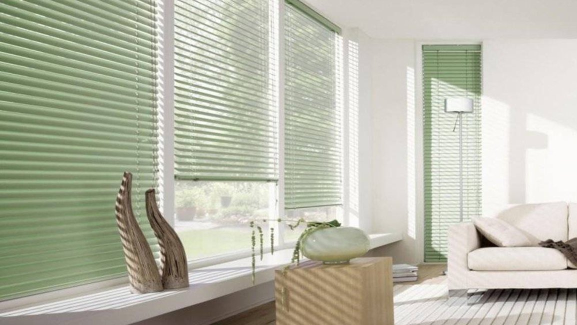 Stylové horizontální žaluzie v jemném zeleném odstínu doplňují světlý interiér a poskytují dokonalou kontrolu nad světlem i soukromím.