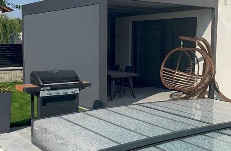 Moderní hliníková pergola u rodinného domu s bioklimatickou střechou, krytým posezením a zakrytým bazénem – prémiové venkovní stínění Hezký stín.