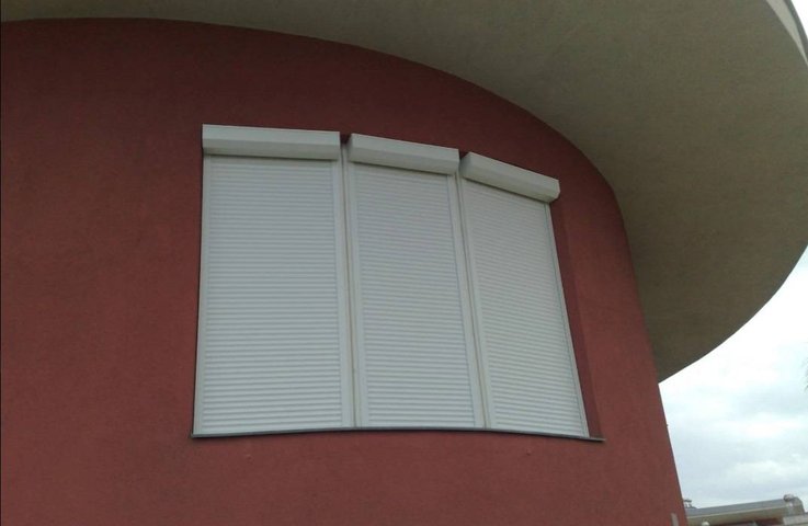 Předokenní rolety na obloukovém okně – tři segmenty s bílými boxy, čisté řešení i pro zaoblenou fasádu.